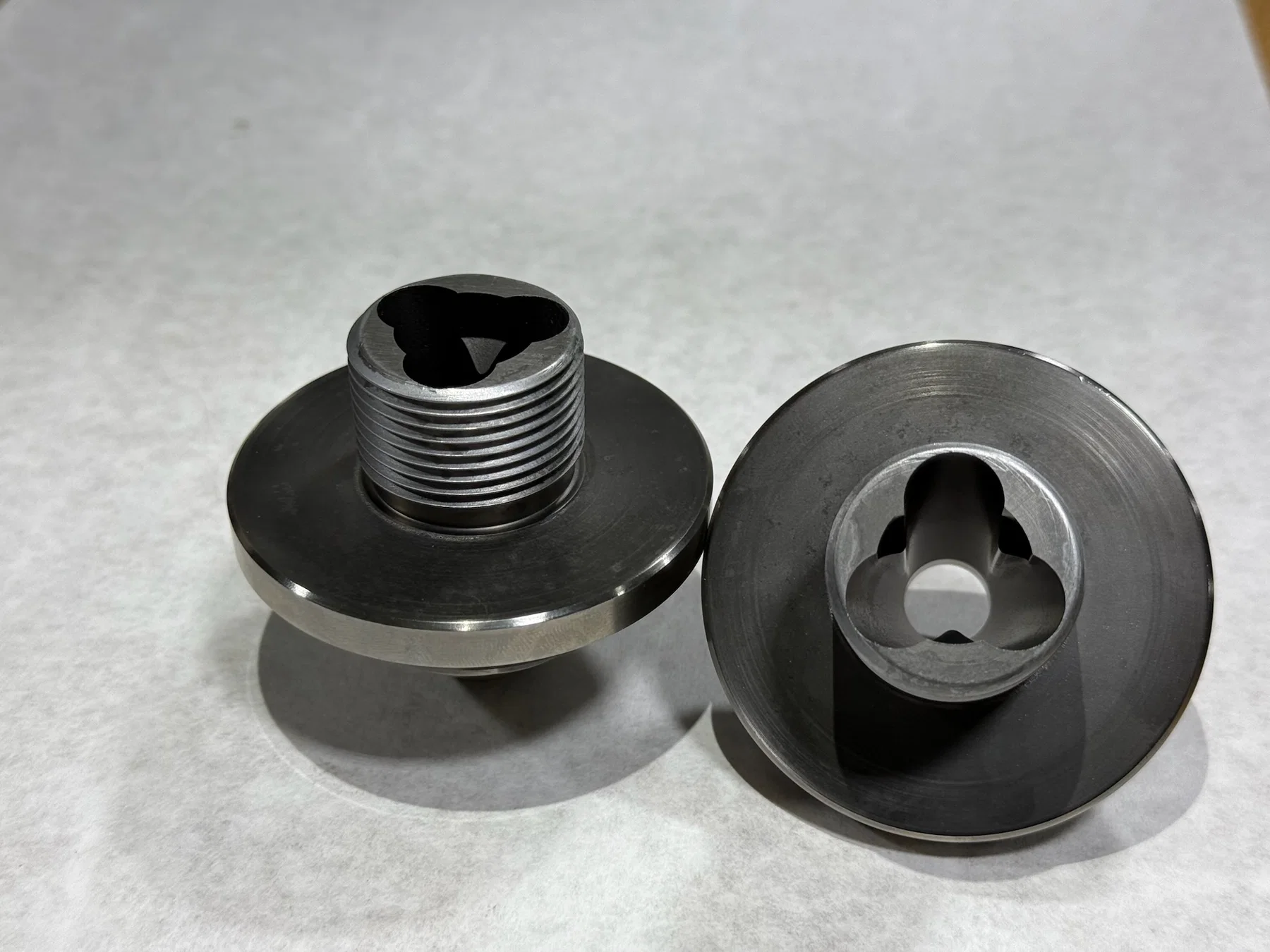 Finished machined components with clean surfaces and threaded details.