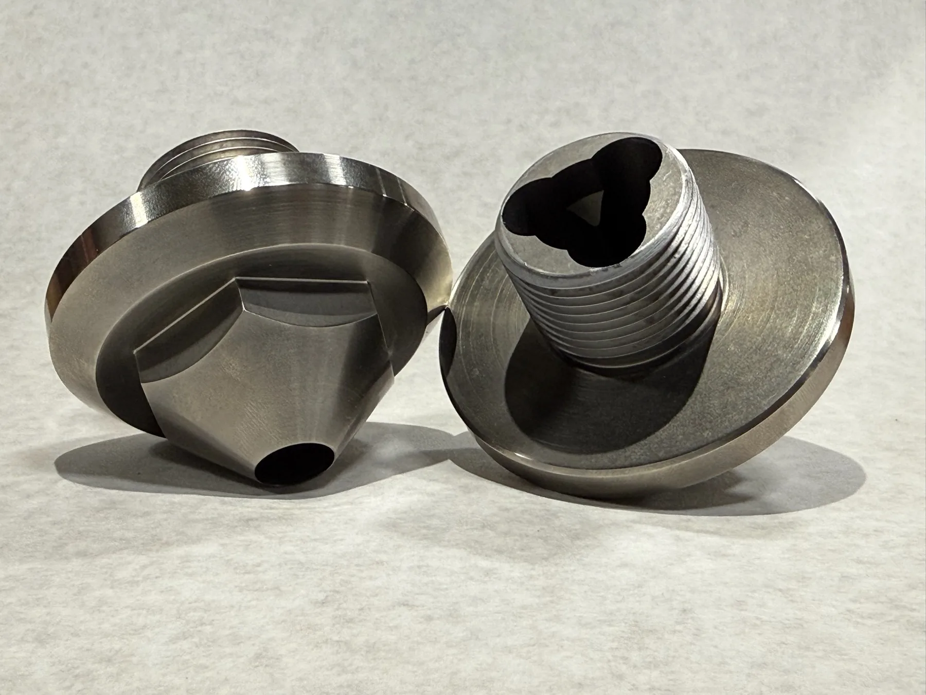 Turned metal components with machined profiles and threaded details.