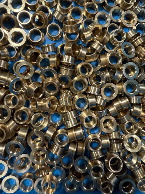 Batch of brass and steel machined components in a shop bin.