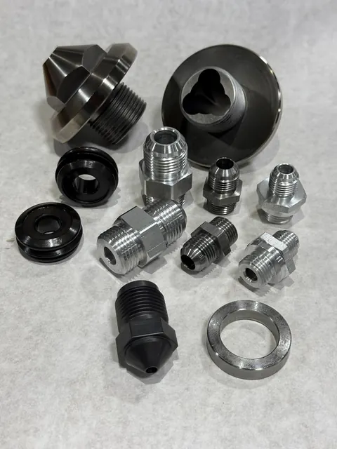 Prototype machined components with small hardware and fittings.